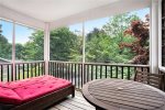 The primary bedroom screen porch has a cafe table and two cushioned loungers